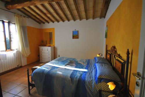 a bedroom with a bed with a blue comforter at Agriturismo la Nicchia in Castelnuovo Berardenga