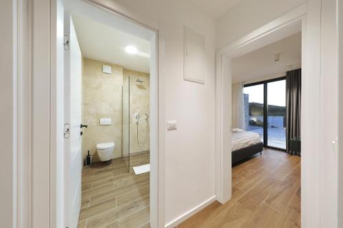 a white bathroom with a shower and a bed at Homes4you K3 in Pašman