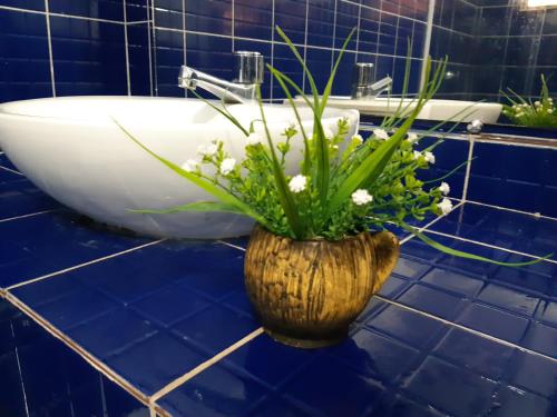 um vaso com flores numa casa de banho com azulejos azuis em Hotel Pousada Villa Calhau em São Luís