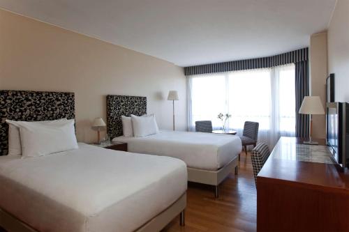 a hotel room with two beds and a desk at NH Córdoba Panorama in Cordoba