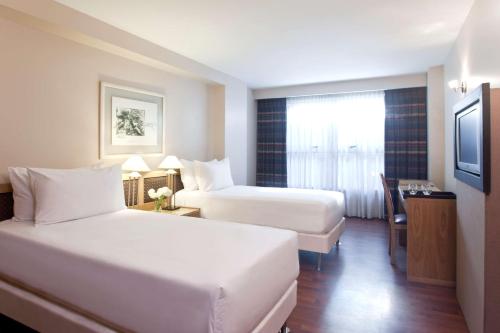 a hotel room with two beds and a television at NH Córdoba Urbano in Córdoba