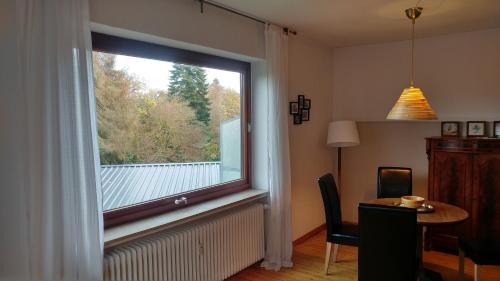 - une grande fenêtre dans une pièce avec une table et une salle à manger dans l'établissement Ferienwohnung Gartenblick, à Worpswede