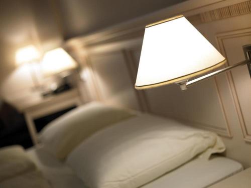 a bedroom with a bed with a lamp on it at Hotel Casino im Park in Kamp-Lintfort
