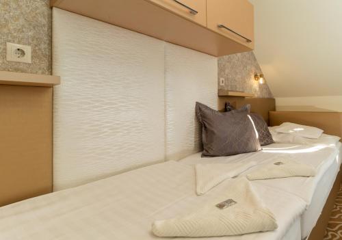two beds in a room with a window with white blinds at Teátrum Boutique Hotel in Győr
