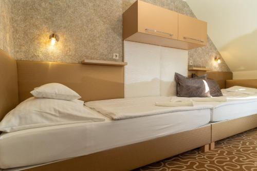 a bed in a room with two white beds at Teátrum Boutique Hotel in Győr