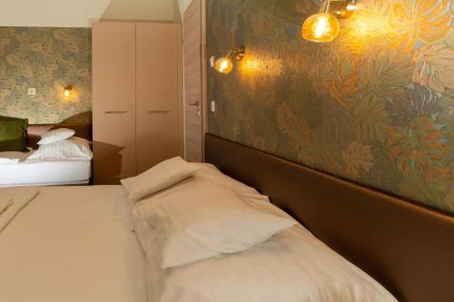 a bedroom with two beds and a painting on the wall at Teátrum Boutique Hotel in Győr