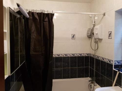 a bathroom with a black shower curtain and a sink at Spacious Bungalow in Romford with parking in Romford