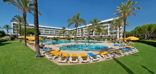 a resort with a pool and chairs and palm trees at Alfagar Alto da Colina in Albufeira