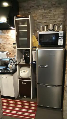 a kitchen with a stainless steel refrigerator and a microwave at Thank you so muchya Miyaco in Kyoto