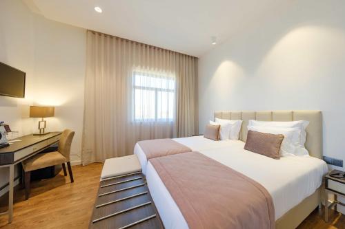 a hotel room with a large bed and a desk at SDivine Fatima Hotel, Congress & Spirituality in Fátima