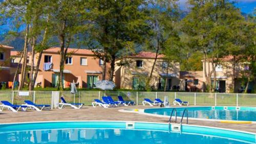 a swimming pool with blue chairs and a house at Domaine de Mélody in Moriani Plage