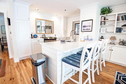a kitchen with white cabinets and a counter with stools at 115 Water Street Inn in Boyne City