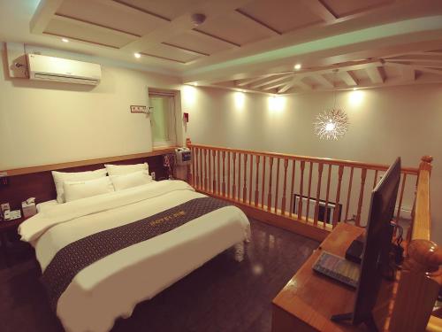 a bedroom with a bed and a desk and a television at Apple Drive-in Hotel in Yeoju