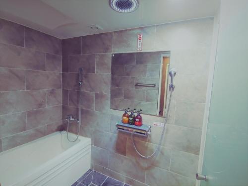 a bathroom with a shower with a tub and a sink at Apple Drive-in Hotel in Yeoju