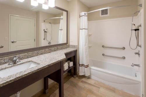 uma casa de banho com um lavatório, uma banheira e um espelho. em GrandStay Hotel & Suites em Cannon Falls
