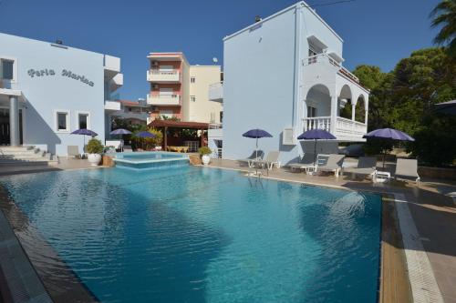 een zwembad met stoelen en parasols naast een gebouw bij Perla Marina Aparthotel in Ialyssos