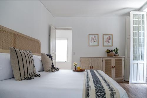 een slaapkamer met een groot bed met witte muren bij Azul Cordoba By The Local Way in Mexico-Stad