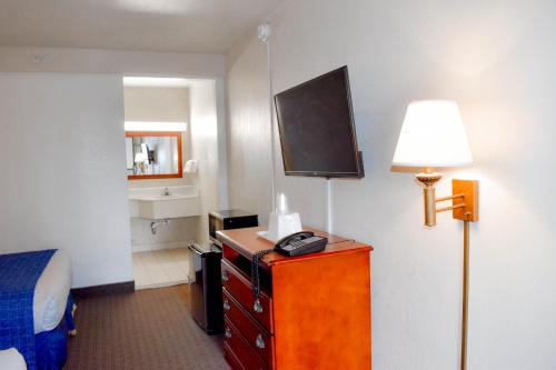 Habitación de hotel con cama y tocador con TV en Attleboro Motor Inn en South Attleboro