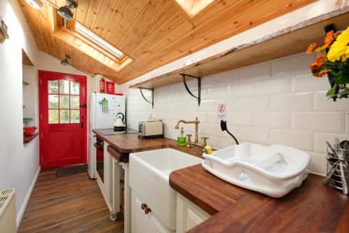 a kitchen with a sink and a red door at The Cottage Hillside in Westport