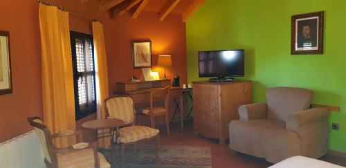 a living room with a television and a desk and chairs at Hotel Sara De Ur in La Cabrera