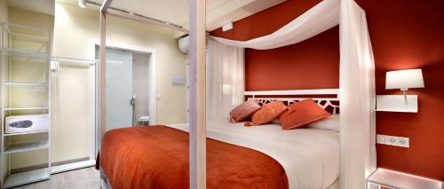 a bedroom with a canopy bed with orange walls at Pensión Plaza Nueva in Bilbao