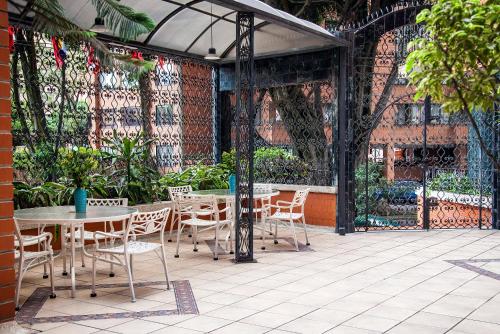 
a patio area with tables, chairs and umbrellas at Hotel Casa Laureles in Medellín
