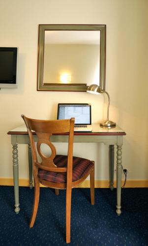a desk with a laptop and a chair and a mirror at Hostellerie du Forez in Saint-Galmier