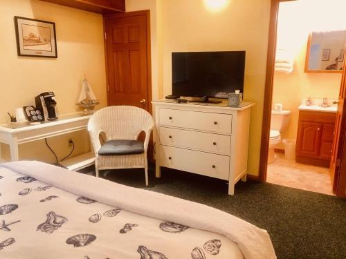 a bedroom with a bed and a dresser with a television at Driftwood Inn in Homer