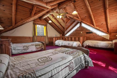 a bedroom with four beds in a log cabin at Casa Puelo Hostería y Cabañas in Lago Puelo