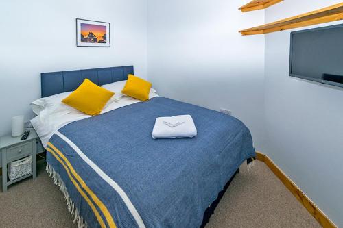 a bedroom with a bed with yellow pillows and a tv at Cosy Cottage Close to East Beach, Shops, Restaurants and RAF base in Lossiemouth