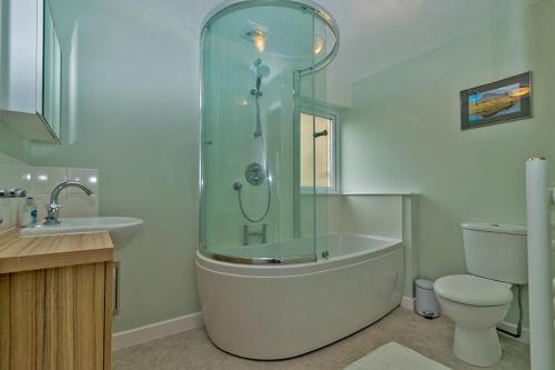 a bathroom with a shower and a tub and a toilet at Cosy Cottage Close to East Beach, Shops, Restaurants and RAF base in Lossiemouth