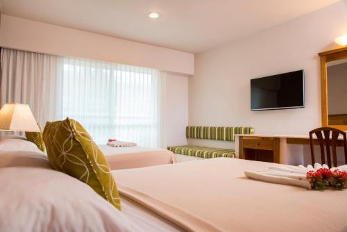 a hotel room with two beds and a flat screen tv at Tecnohotel Mérida Norte in Mérida