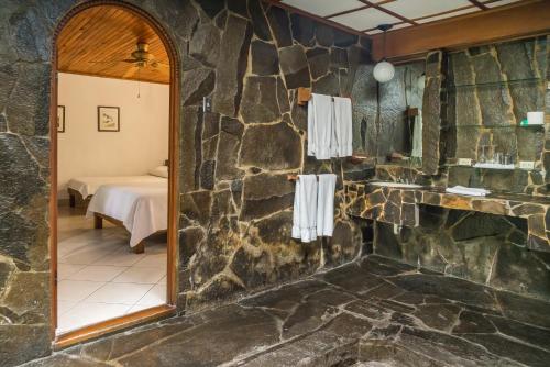 a bathroom with a stone wall and a mirror at Costa Verde Inn in San José