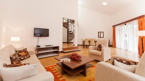 een woonkamer met witte meubels en een televisie bij Heri Heights Serviced Apartments by Trianum in Nairobi
