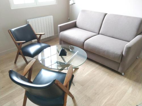 uma sala de estar com um sofá e uma mesa de vidro e cadeiras em Appartement au centre de Saint Briac em Saint-Briac-sur-Mer