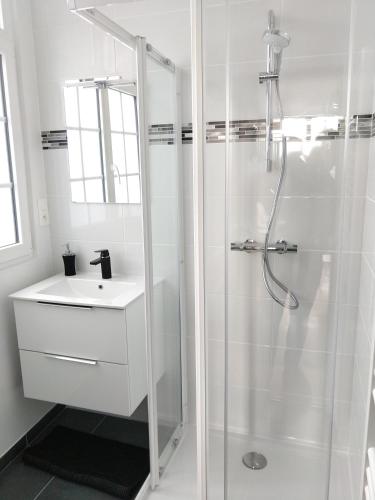 une salle de bain blanche avec une douche et un lavabo dans l'établissement Appartement au centre de Saint Briac, à Saint-Briac-sur-Mer