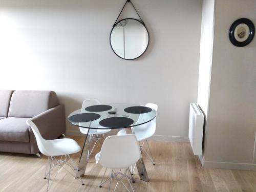 a dining room table with white chairs and a mirror at Appartement au centre de Saint Briac in Saint-Briac-sur-Mer