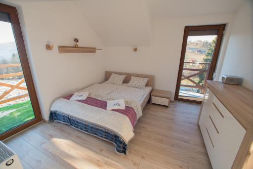 ein kleines Schlafzimmer mit einem Bett und einem großen Fenster in der Unterkunft Chata Pod Górką in Wisła