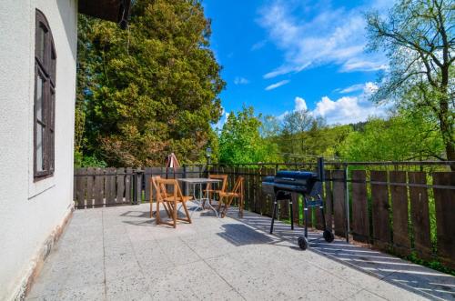 a patio with a table and chairs and a grill at Borovnička in Borovnička