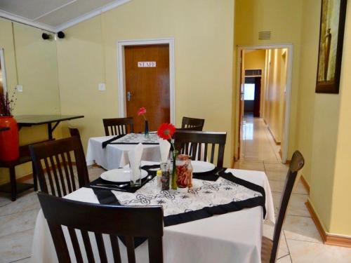 uma sala de jantar com uma mesa com uma toalha de mesa branca em Lilliz Guest House em Mthatha