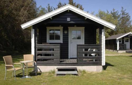 a small house with two chairs and a table in the grass at Løkken Klit Camping & Cottage Village in Løkken