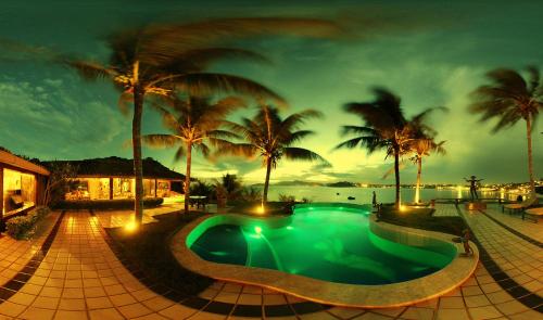 a swimming pool in a resort with palm trees at Bravacasa Geriba B&uacute;zios Luxury Inn in B&uacute;zios