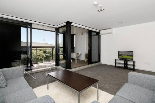 a living room with a couch and a table at Central Mount Apartment, Quiet and Spacious with Pool in Mount Maunganui