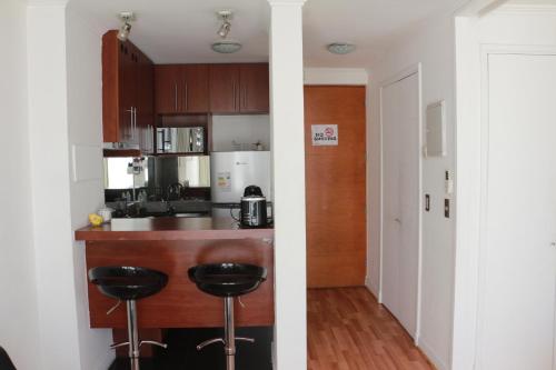 a kitchen with a counter and stools in a room at Austral Rentahome Nueva Providencia in Santiago