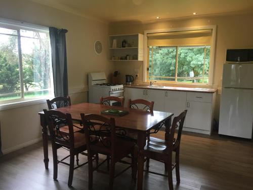 a kitchen with a table and chairs and a refrigerator at Neerim Country Cottages in Neerim South