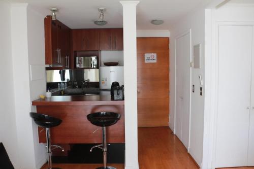 a kitchen with a counter and stools in a room at Austral Rentahome Nueva Providencia in Santiago