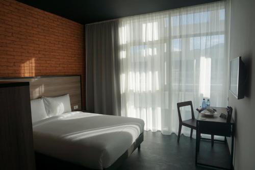 a bedroom with a bed and a table and a window at ONOMO Hotel Tanger Med in Tangier
