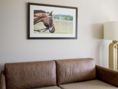 a couch in a living room with a picture of a horse on the wall at The William Inglis Mgallery in Warwick Farm