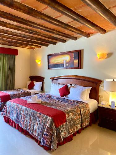 a bedroom with two beds with red and white pillows at Hotel El Campanario Playa del Carmen in Playa del Carmen