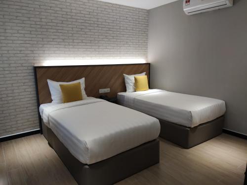 a hotel room with two beds and a brick wall at Hotel 99 Seri Kembangan Serdang in Seri Kembangan